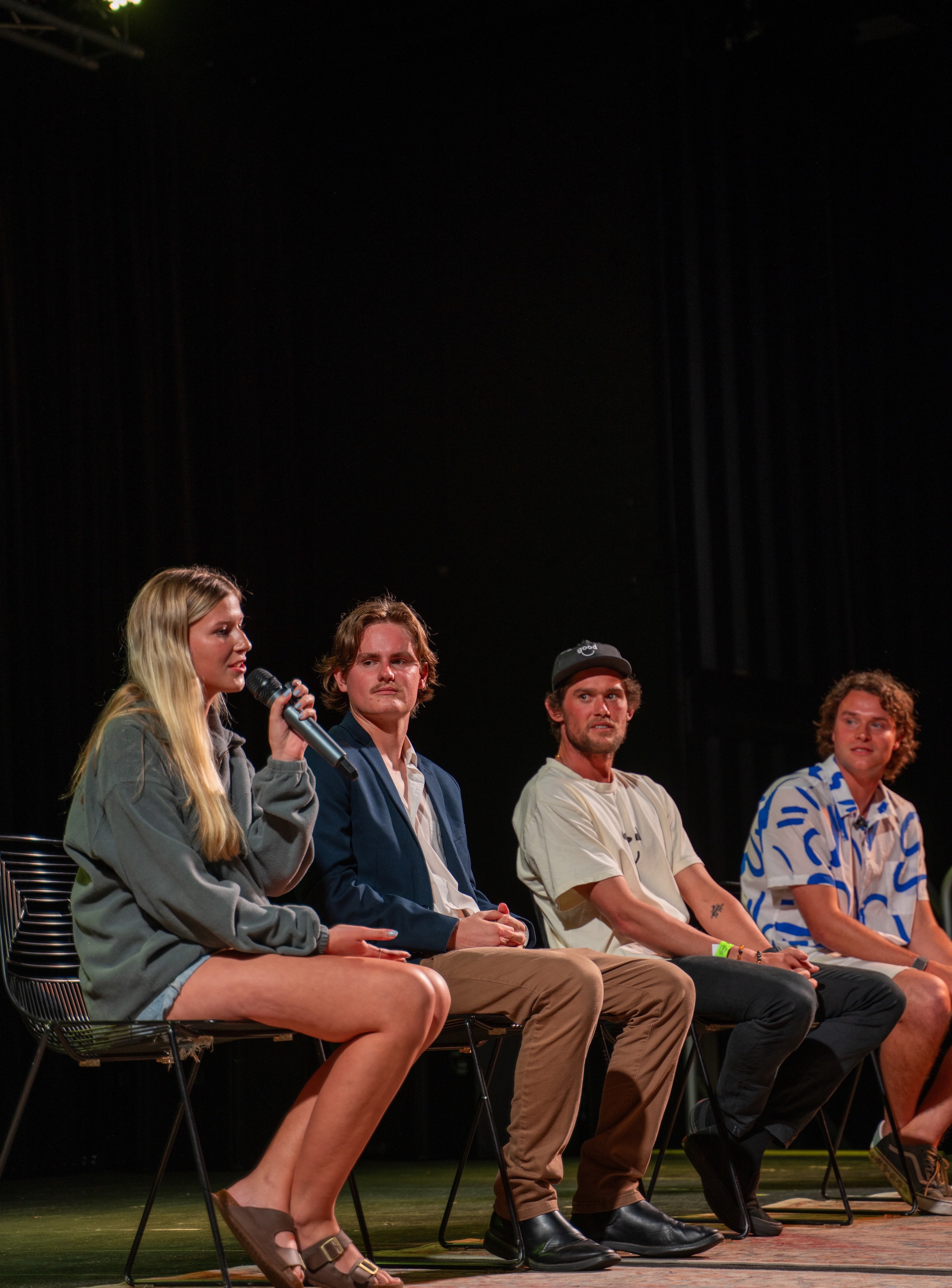 Four people sitting on a stage with microphones, likely participating in a panel discussion.